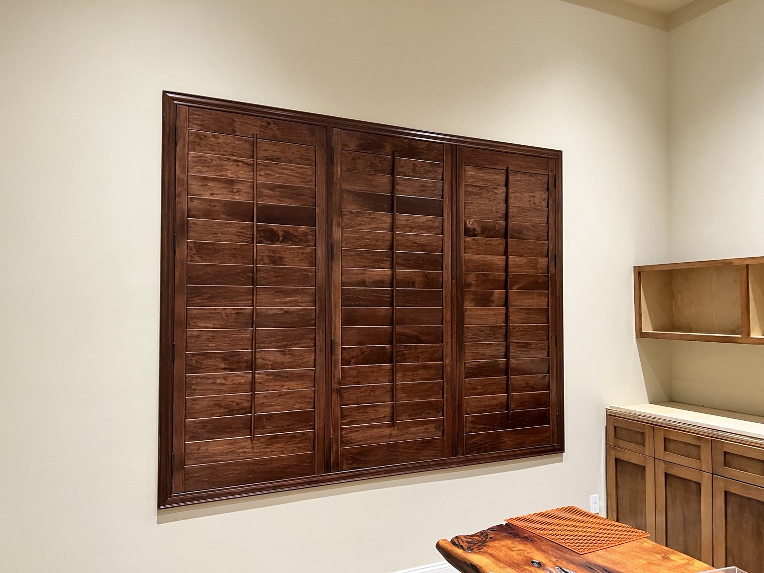 Stained wood plantation shutters installed in a custom interior